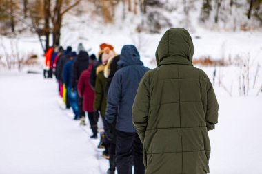 Karlı zeminde bir grup insanın yürüyüşü.