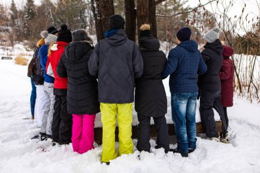 A group of people stood around a tree and taking hands of each other
