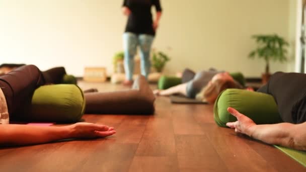 Group of people lying in shavasana exercising — Stock video