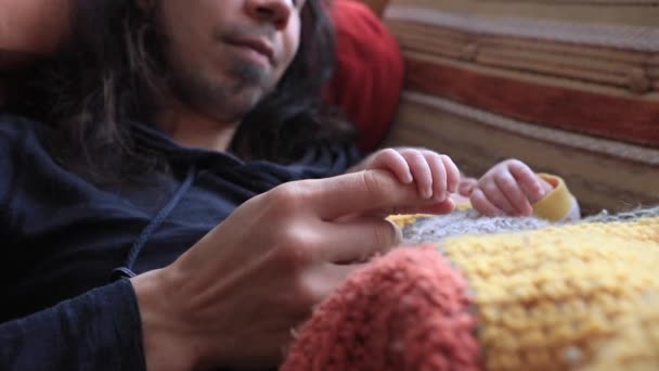 Малыш спит с отцом, держа палец — стоковое видео