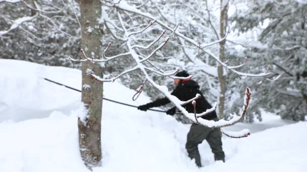 Энергичный человек зимой убирает снег с крыши — стоковое видео
