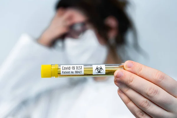 Stress-out verpleegkundige houdt covid 19 injectieflacon voor laboratoriumtest — Stockfoto
