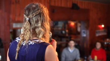 Genç bir kadın sahnede konuşma yapıyor.