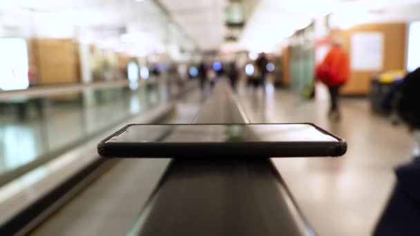 A smartphone on moving walkway handrail. — Stock Video