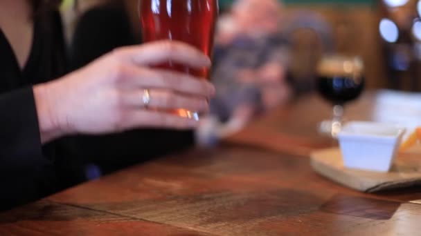 Женщина поднимает стакан пива для глотка — стоковое видео