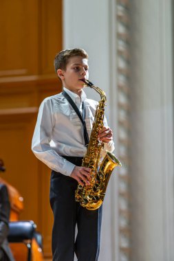 20.02.15, Moskova, Rusya. Müzik okulunun orkestra ve solistlerinin konseri Alekseev 'den sonra isimlendirildi. Genç saksafoncu sahnede bir parça çalıyor..