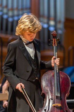 20.02.15, Moskova, Rusya. Müzik okulunun orkestra ve solistlerinin konseri Alekseev 'den sonra isimlendirildi. Genç çellocu çocuk ve piyanist kız gösteriden önce sahnede duruyorlar..
