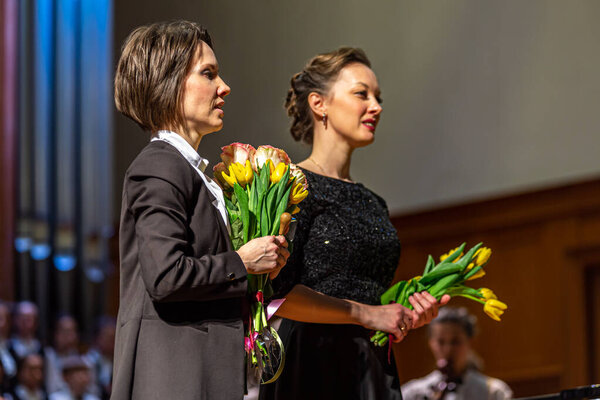 2020.02.15, Moscow, Russia. reporting concert of the orchestra and soloists of secondary and senior students of the music school named after Alekseev. women choir and orchestra conductors with flowers on stage.