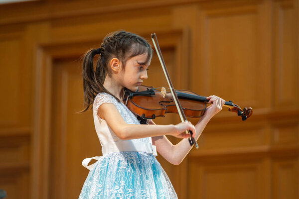 2020.02.15, Moscow, Russia. reporting concert of the orchestra and soloists of secondary and senior students of the music school named after Alekseev. Girl violonist on the stage.