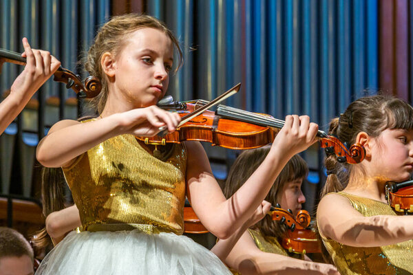 2020.02.15, Moscow, Russia. reporting concert of the orchestra and soloists of secondary and senior students of the music school named after Alekseev. Group of girls violinists on stage.