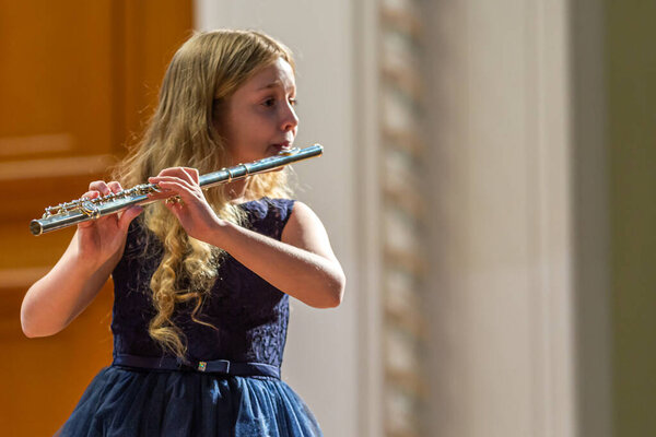 2020.02.15, Moscow, Russia. A group of young flutists stands on stage playing classical composition at music school.