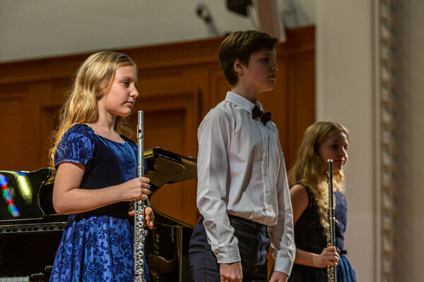 2020.02.15, Moscow, Russia. A group of young flutists stands on stage after a performance of applause.