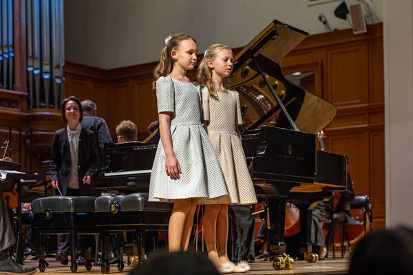 2020.02.15, Moscow, Russia. reporting concert of the orchestra and soloists of secondary and senior students of the music school named after Alekseev. Two girls going to play four hands concert. 