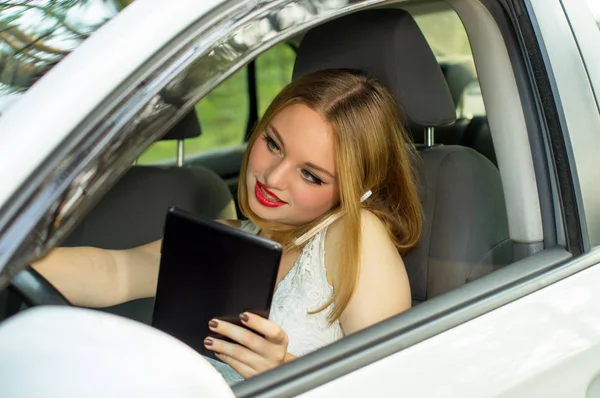 En ung flicka som arbetar när du kör bil — Stockfoto