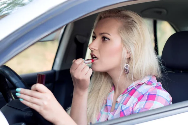 Mädchen malt sich am Steuer des Autos die Lippen — Stockfoto