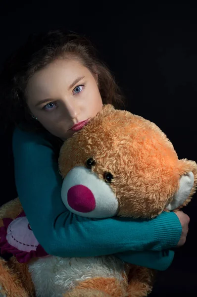 Tiener depressie, een meisje een teddy bear knuffelen in het donker — Stockfoto