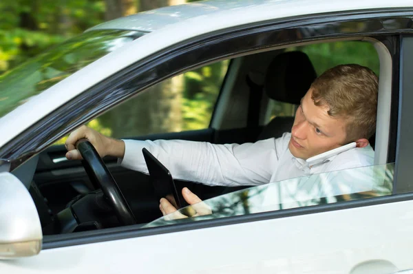 젊은 남자는 자동차의 바퀴 뒤에 전화를 사용 하 여 — 스톡 사진