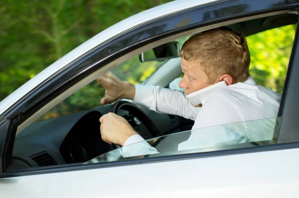 El joven usa el teléfono al volante de un auto. — Foto de Stock