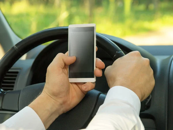 Jovem usa um telefone celular, dirigindo um carro — Fotografia de Stock