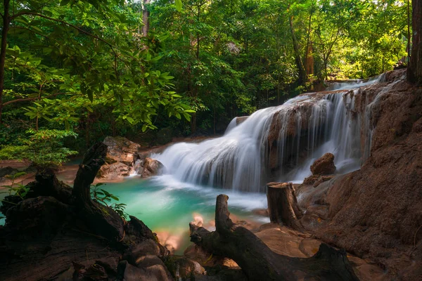 Waterfalls and fish swim in the emerald blue water in Erawan Nat
