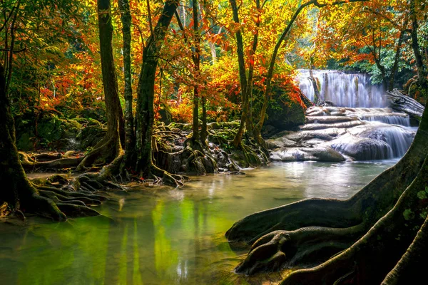 Waterfalls and fish swim in the emerald blue water in Erawan Nat