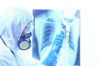 Coronavirus ya da Covid-19 konsepti, koruyucu kıyafetli erkek doktor hastanedeki hastalara ilaç veriyor. Akciğer röntgeni film imha geçmişi. Sığ odak etkisi.