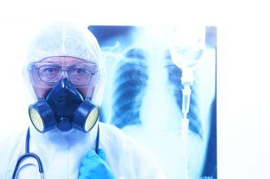 Coronavirus ya da Covid-19 konsepti, koruyucu kıyafetli erkek doktor hastanedeki hastalara ilaç veriyor. Akciğer röntgeni film imha geçmişi. Sığ odak etkisi.