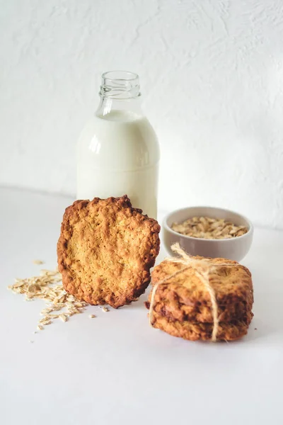 Galletas de avena y una botella de vidrio con leche sobre un fondo claro, una nutrición saludable. Desayuno o merienda por la noche — Foto de Stock