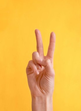 Renkli arka planda barış veya zafer jesti gösteren genç bir kadın