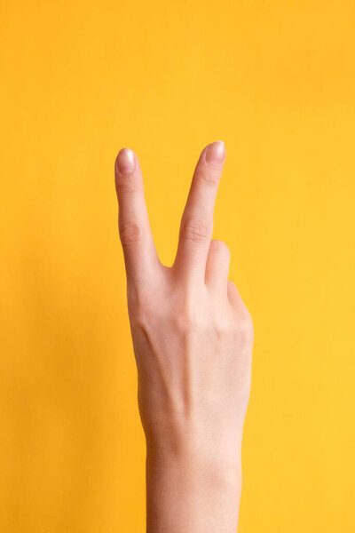 Young woman showing peace or victory gesture on color background