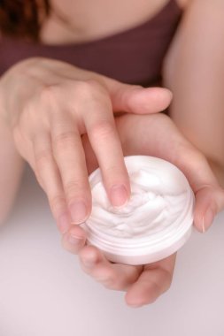 Güzel vücut ve cilt kremi hafif bir arka plan üzerinde elleriyle kadının bakımlı.