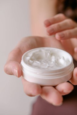 Güzel vücut ve cilt kremi hafif bir arka plan üzerinde elleriyle kadının bakımlı.