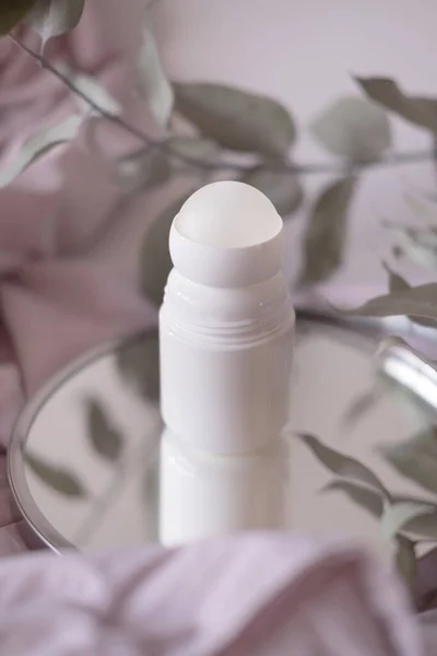 Mock up bottle of deodorant on a background of eucalyptus foliage. Soft focus. Light background — 图库照片