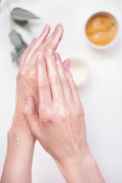 Uma jovem cuida das mãos com um esfoliante. Conceito de autocuidado, cuidados com as mãos, cuidados com o corpo — Fotografia de Stock