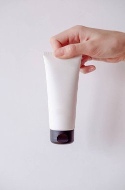 Young female hand holds minimalistic mockup cosmetic packaging. Mock-up for branding and label.