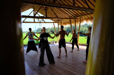 Ubud, Bali, Endonezya - 23 Aralık 2019: Bir grup insan pirinç tarlaları arasında bambu terasında qigong antrenmanı yapıyor.