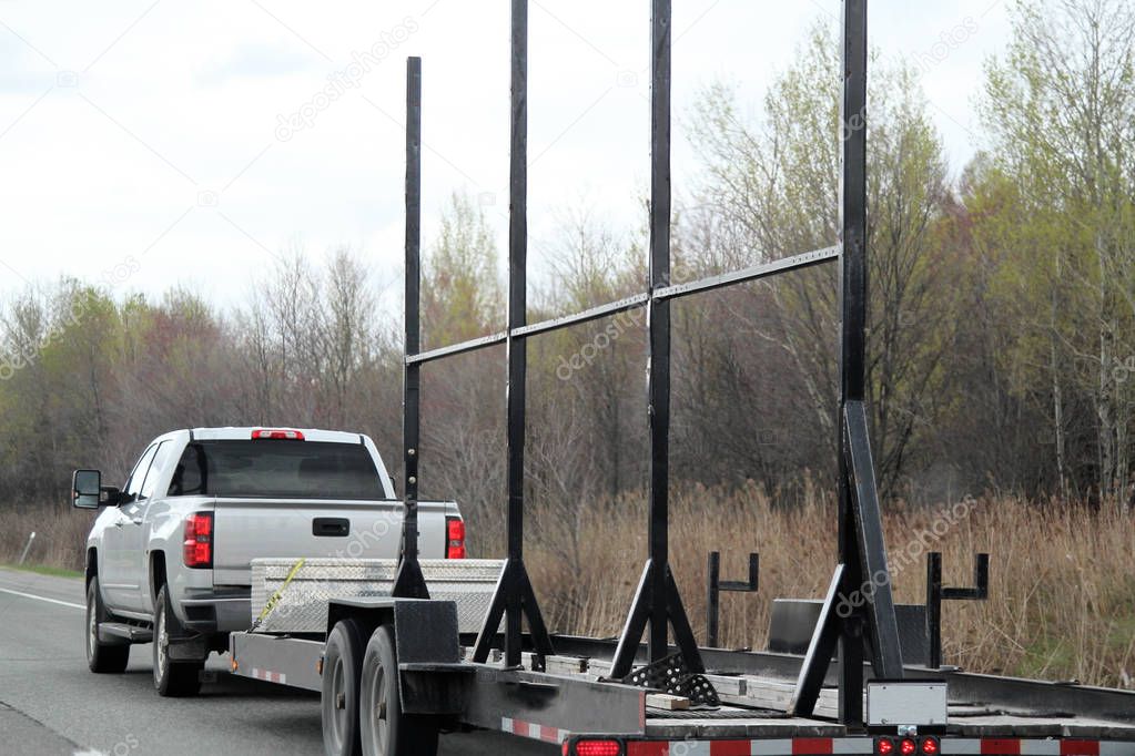 White truck pulling a trailer with metal supports for signs