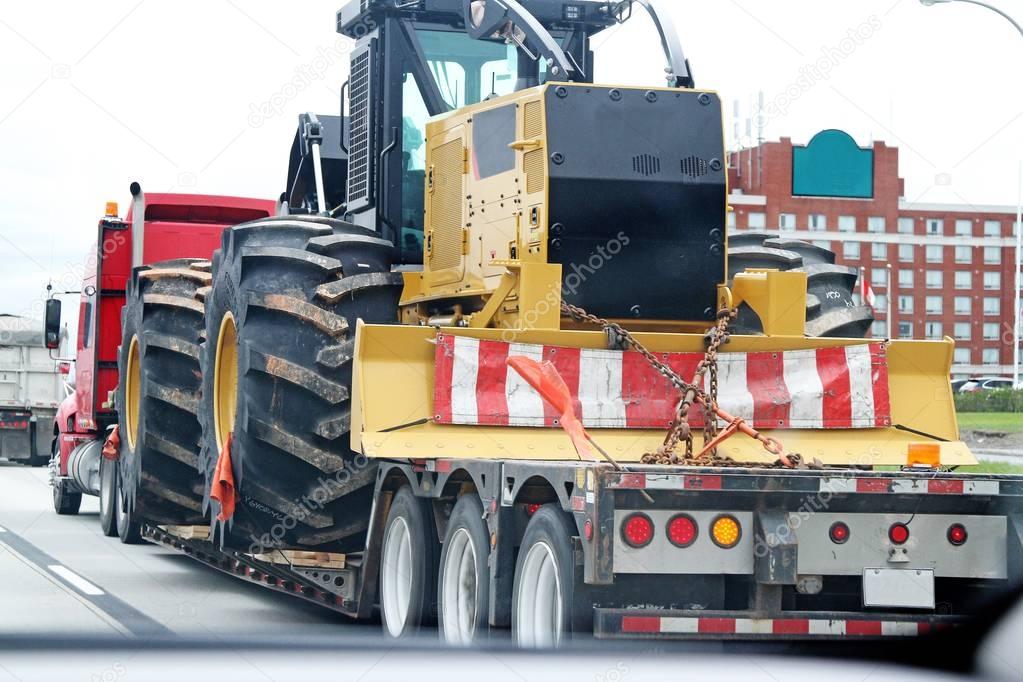 Tractor with large wheels on flatbed