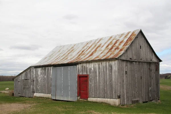 Velho celeiro de madeira abandonada com porta vermelha — Fotografia de Stock