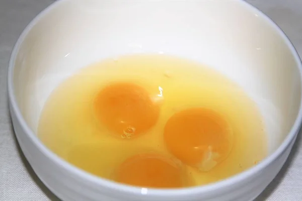 Tres huevos agrietados en un tazón blanco — Foto de Stock