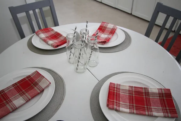 Küchentisch Mit Tellern Servietten Glasflaschen Und Strohhalmen — Stockfoto