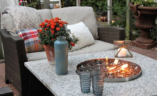 Outdoor seating arrangement around a gas fire pit table in the fall