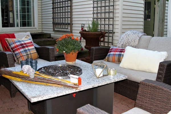 Outdoor seating arrangement around a gas fire pit table in the fall