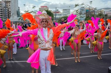Parlak kırmızı elbiseli bir sütun önünde bir adam dansları.