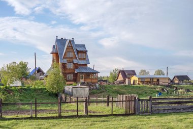 Büyük bir ev ve bir sera ile sebze bahçesi ile kırsal manzara.