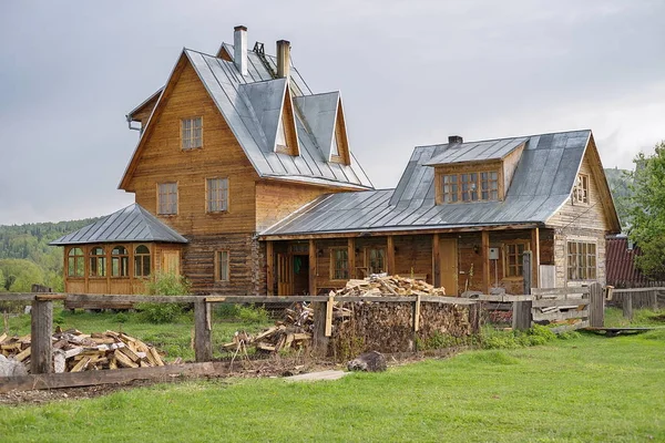 Grote rustieke houten huis met hout in de buurt van door. — Stockfoto