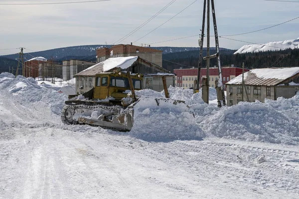 Η μπουλντόζα καθαρίζει ο δρόμος από το χιόνι στο δρόμο. — Φωτογραφία Αρχείου