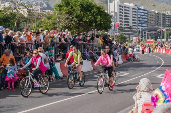 I ciclisti percorrono il viale delle feste con le persone sullo sfondo della città . — Foto Stock