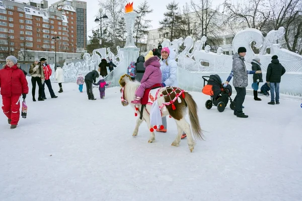 Het kind is het berijden van een paard op de achtergrond van de dia van een ijs. — Stockfoto