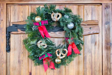 Çubuk kraker, kırmızı yay ve ahşap Kapıda asılı altın süs eşyaları ile Noel çelenk.